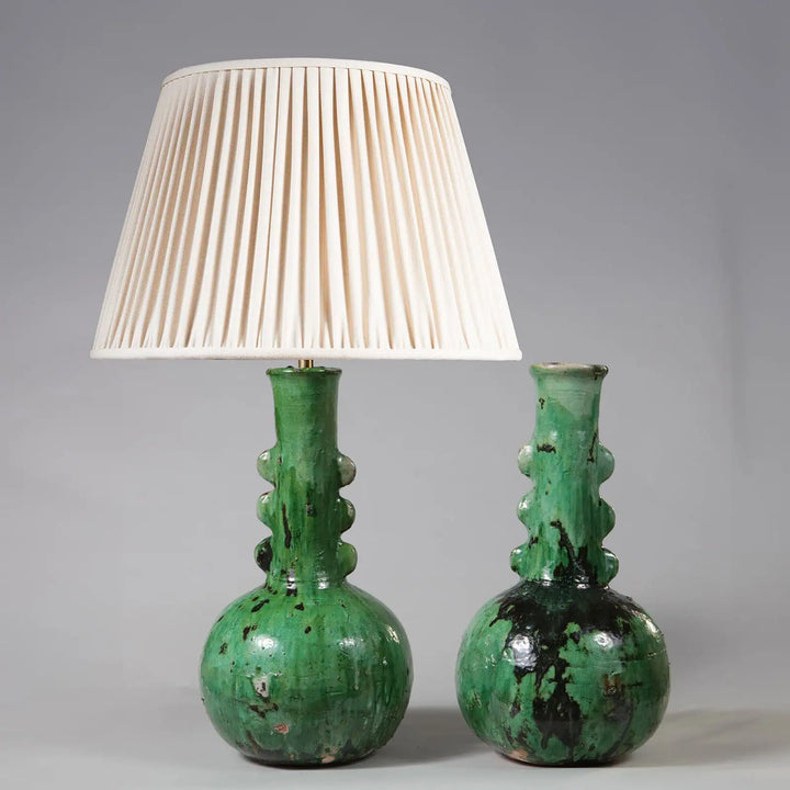 Pair of Green Glazed Bottle Vases as Table Lamps with textured green glaze and cream pleated lampshade, 60 cm tall.