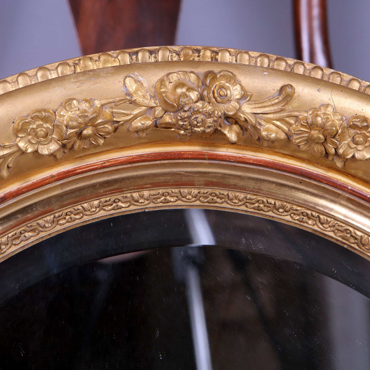 Pair of Victorian Giltwood Oval Wall Mirrors with floral carved giltwood frame and beveled mercury plates, circa 1880 England.
