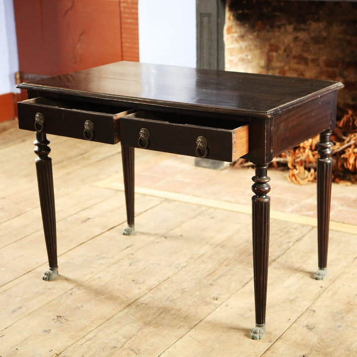 Anglo Indian Ebonised Writing Table with two drawers, lion mask handles, fluted legs, and brass paw feet circa 1860.