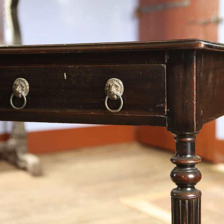 Anglo Indian Ebonised Writing Table with lion mask drawer handles and fluted tapering legs on brass paw feet.