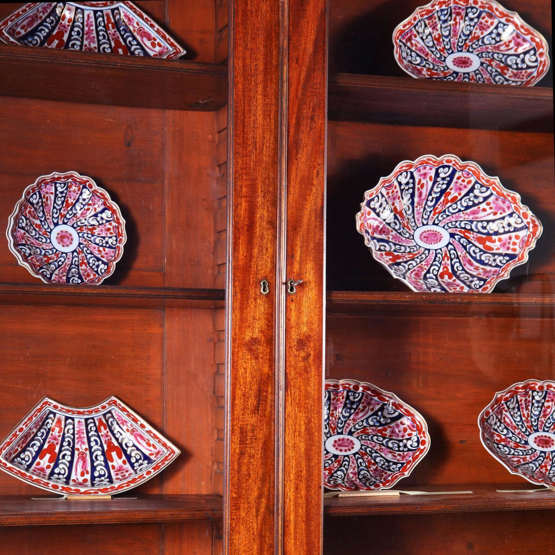 George III Chippendale period mahogany breakfront bookcase with glazed doors displaying decorative plates.