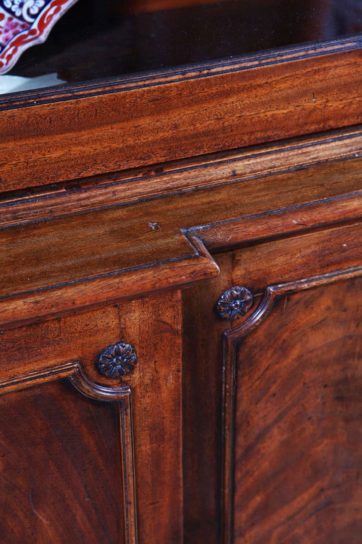 George III Chippendale period mahogany breakfront bookcase close-up showing carved paterae and wood grain details.
