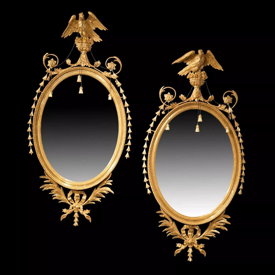 Pair of George III Giltwood Oval Mirrors with neoclassical eagles, tassels, and palm leaf decorations, circa 1770 England.