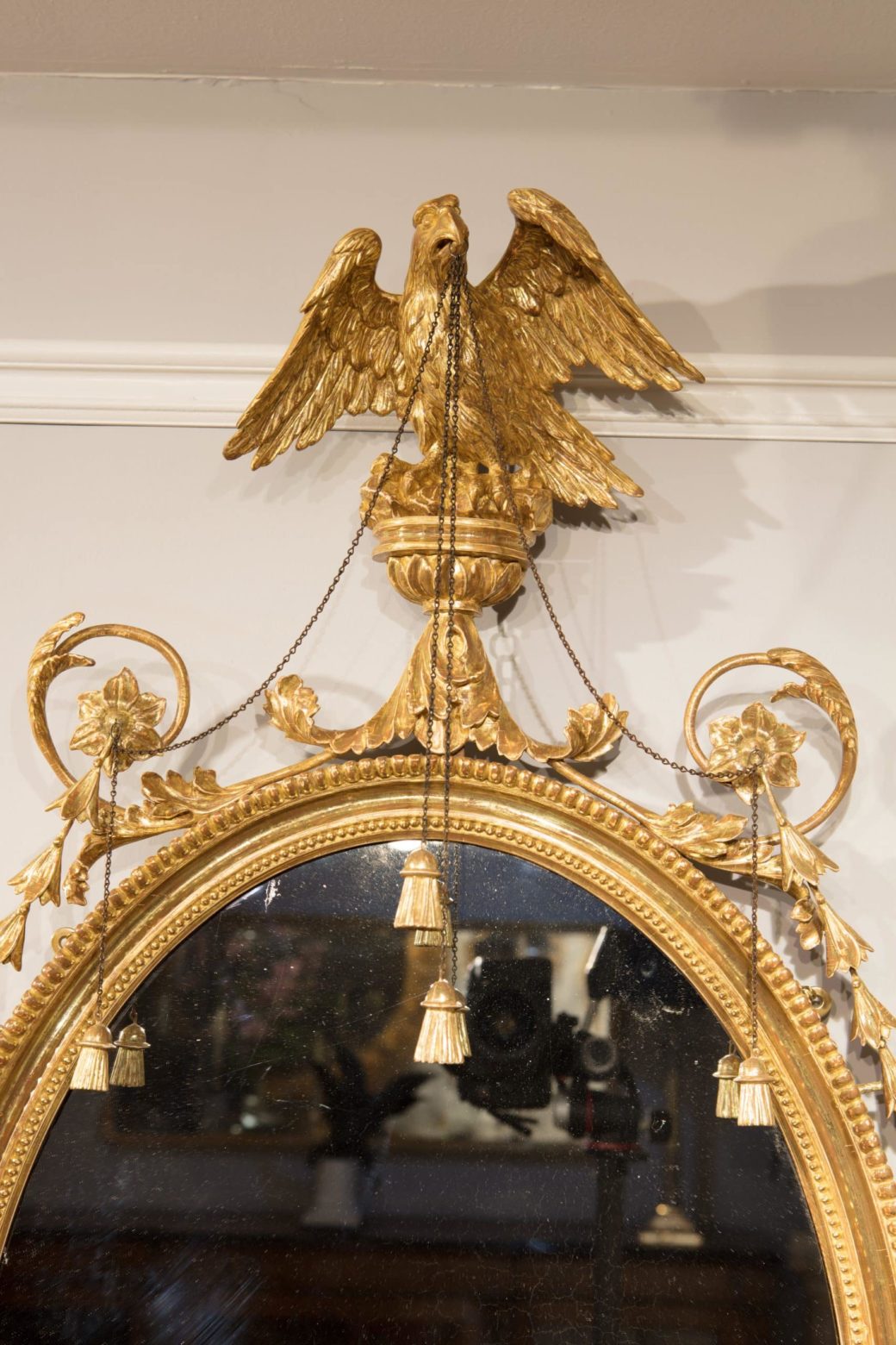 Pair of George III Giltwood Oval Mirrors with gilt eagle, trailing harebells, chains, and tassels, English circa 1770.