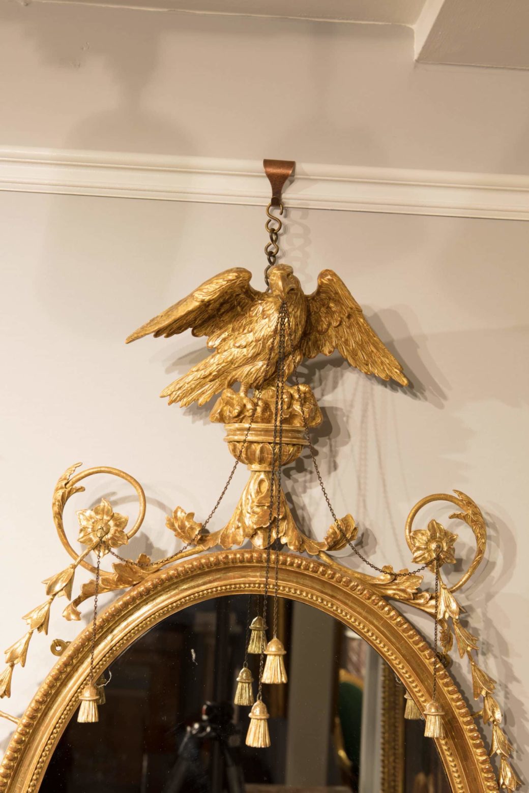 Pair of George III Giltwood Oval Mirrors with gilt eagle, tassels, harebells, and palm leaf details, England circa 1770.