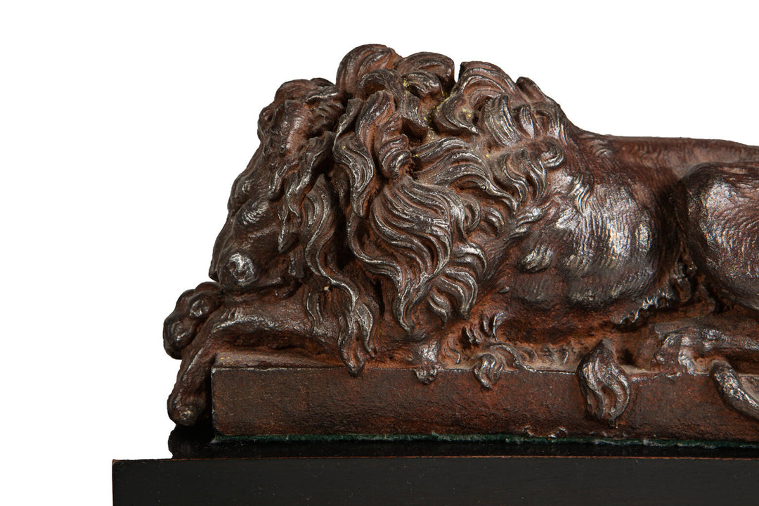 Pair of Cast Iron Versions of the Canova Lions sculpture showing a detailed sleeping lion with bronze patina.