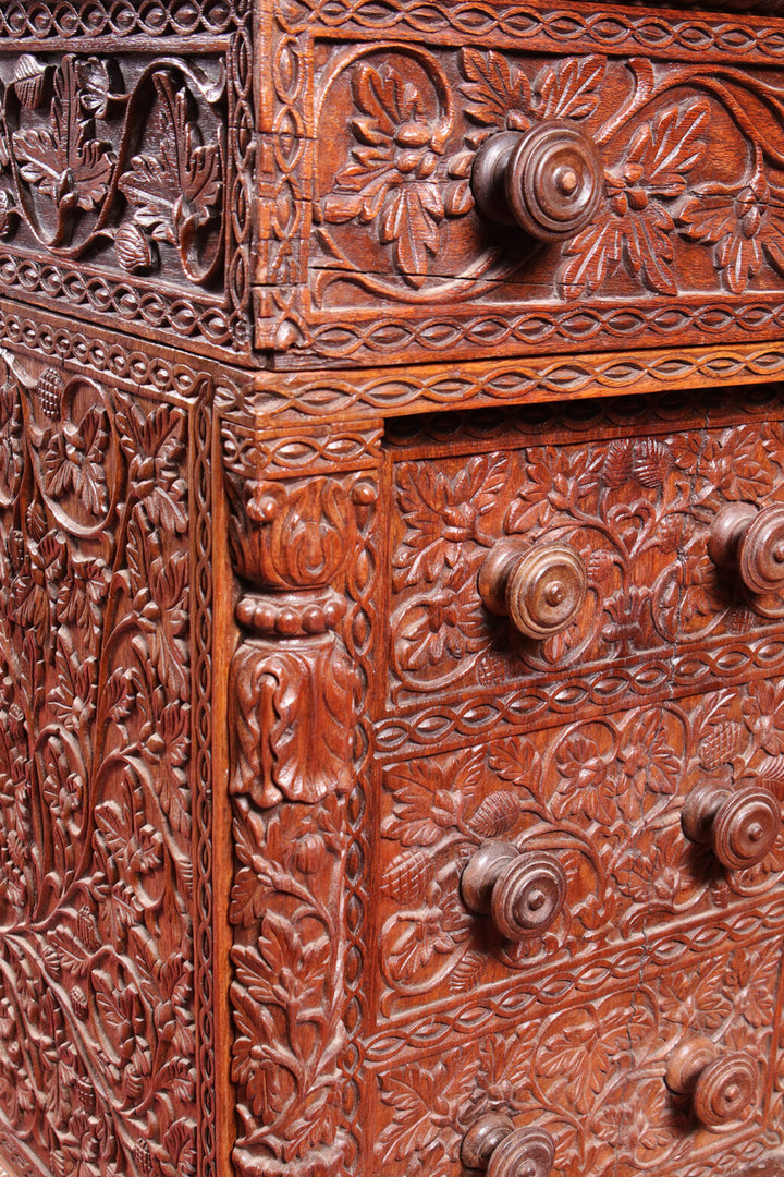 Anglo Indian Teak Pedestal Desk with intricate floral carvings and wooden knobs on drawer fronts.