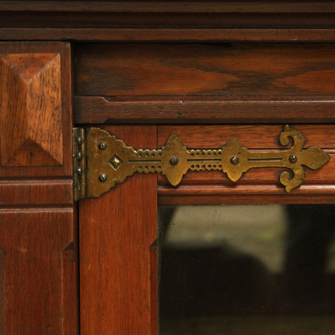 Aesthetic Movement Breakfront Bookcase close-up of oak wood and decorative brass hinge on glazed door.