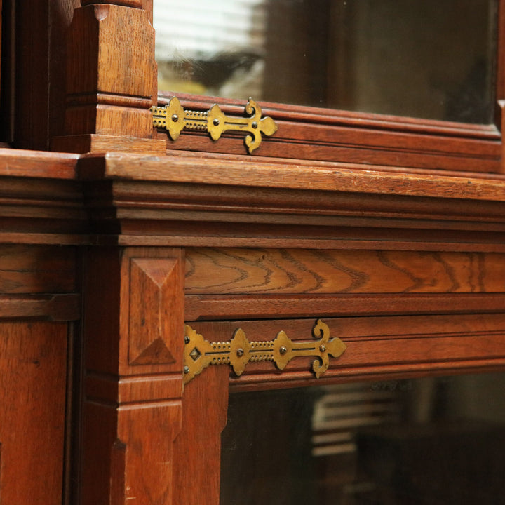 Aesthetic Movement Breakfront Bookcase oak wood with detailed brass hinges and carved decorative elements close-up view