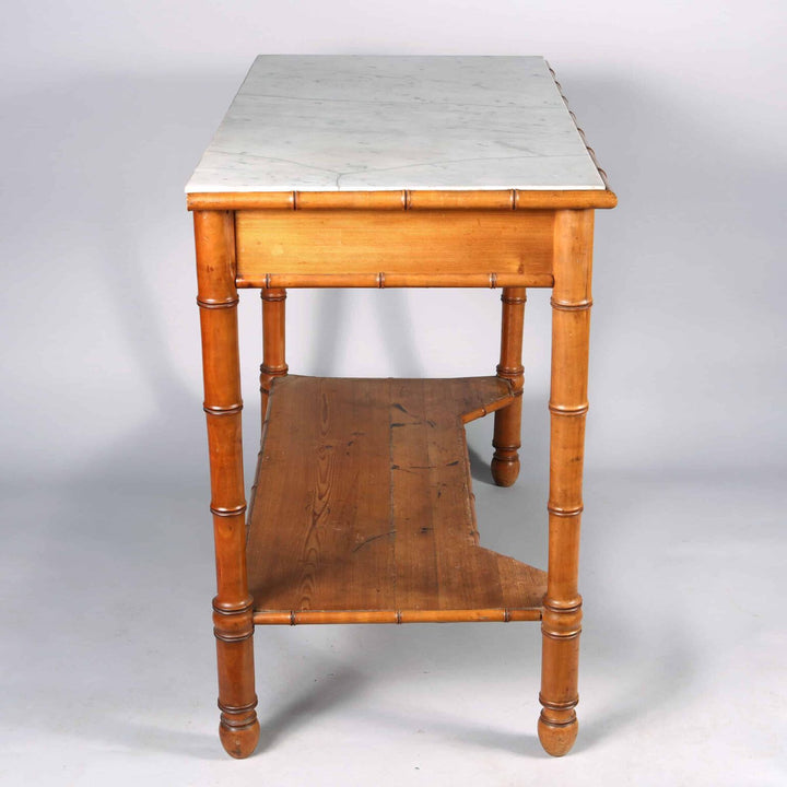 A Napoleon III simulated bamboo console desserte with white marble top, two drawers, and lower wooden tier.