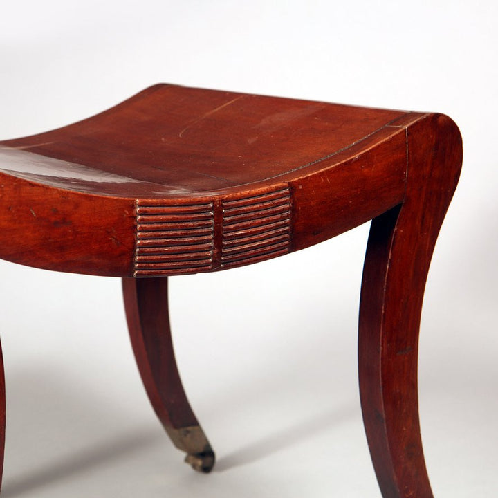 A Regency mahogany sabre legged saddle stool