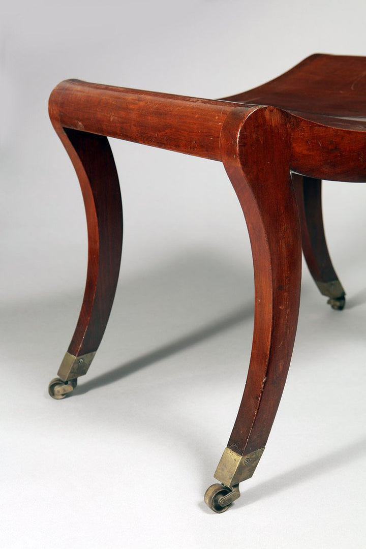 A Regency mahogany sabre legged saddle stool
