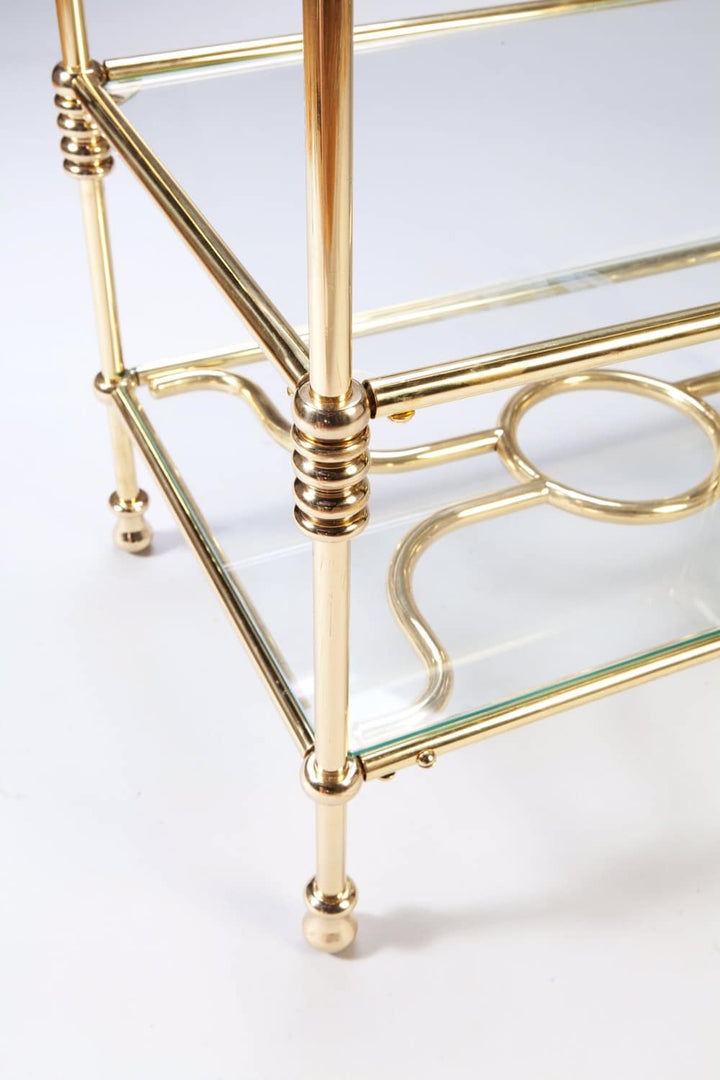 A Three Tiered Brass Art Deco Etagere with detailed rings on polished brass columns and glass shelves.