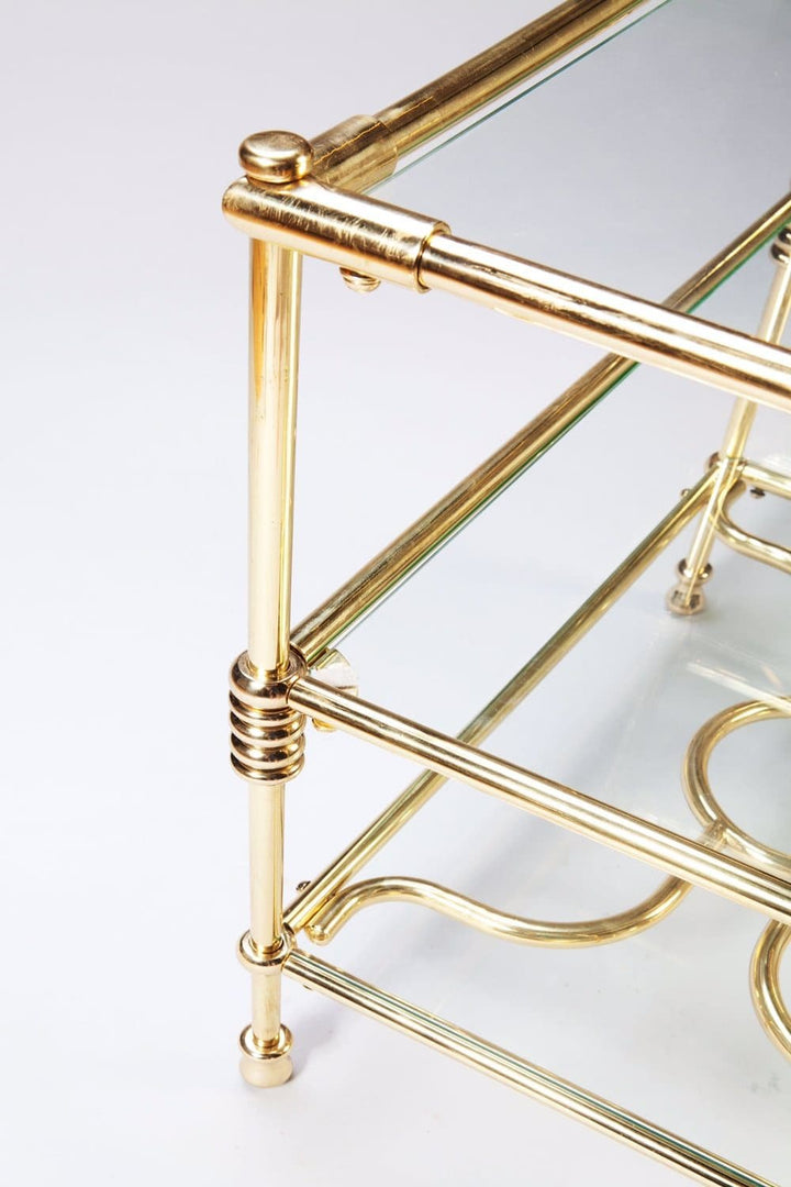 A close-up of the brass frame detailing on the Three Tiered Brass Art Deco Etagere with glass shelves.