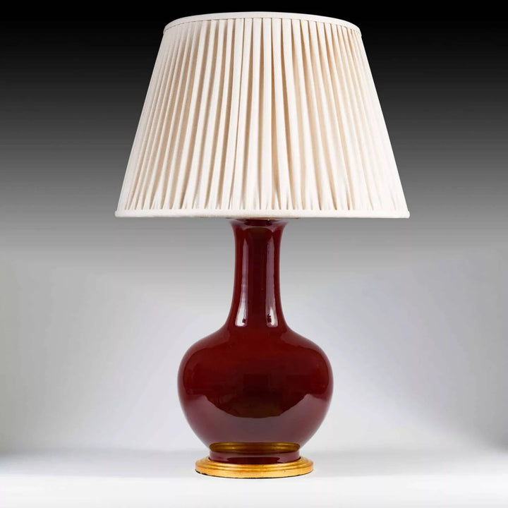 Chinese Sang de Boeuf Glazed Vase mounted as a Table lamp with pleated cream shade and gilt wooden base.