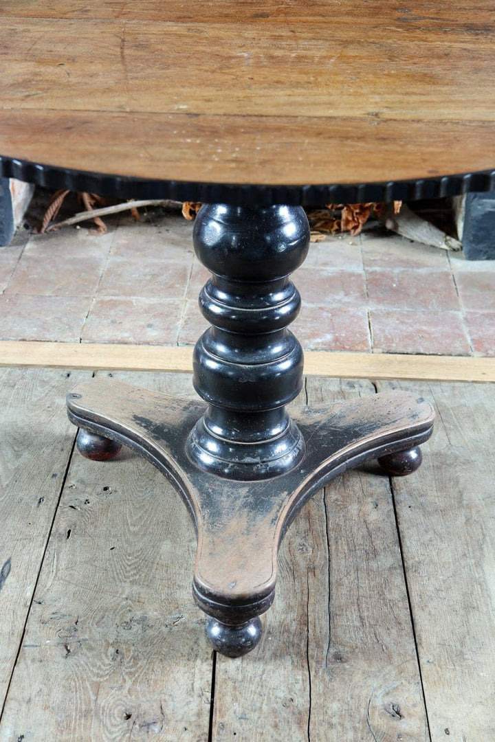 Anglo Indian Tilt Top Pedestal Centre Table with circular top, ebonized pedestal base, and triangular bun feet base.