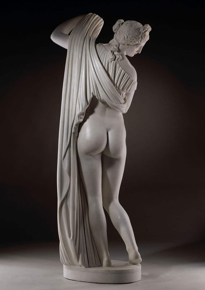 Callipygian Venus marble statue showing the back view of a woman holding draped cloth over her shoulder