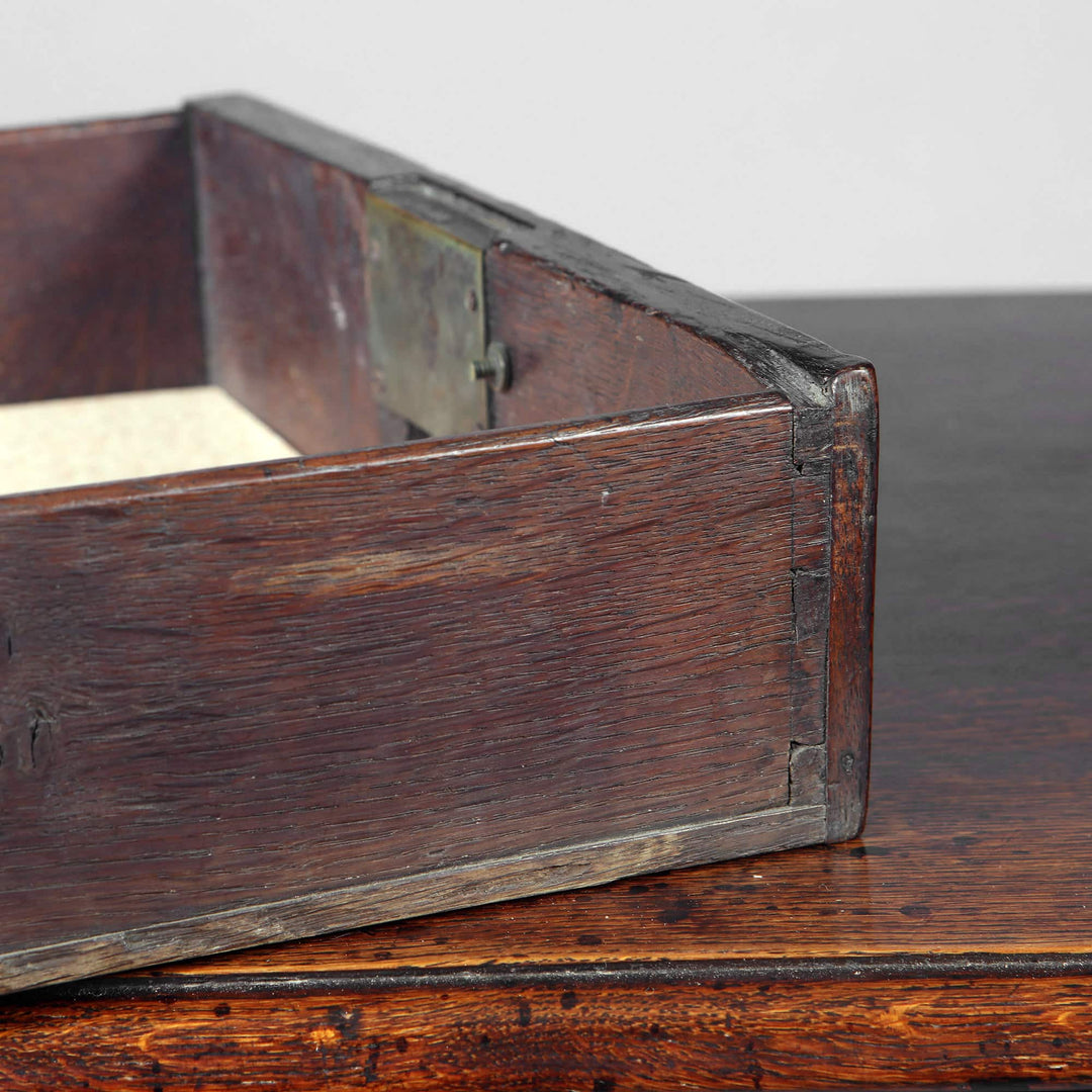 George I Oak Lowboy antique drawer corner showing wood grain, brass hardware, and dovetail joints on oak surface.