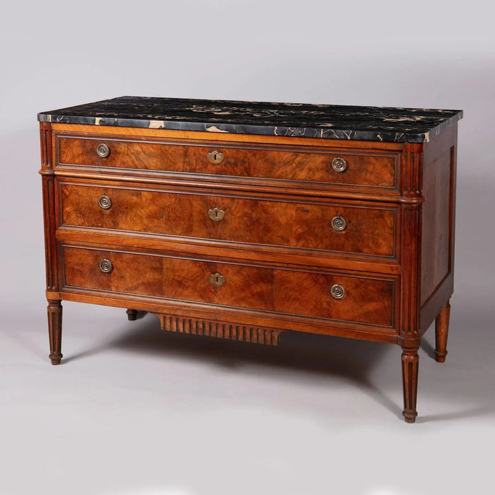 A French provincial Louis XVI commode with burr walnut veneer, Nero Portoro marble top, and fluted legs, stamped COURTE.