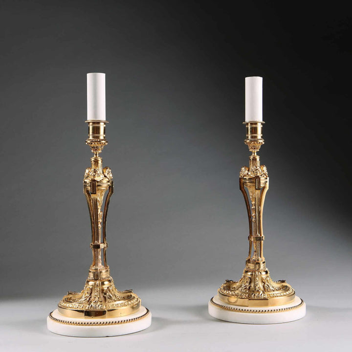Pair of French Gilt Bronze Neo Classical Candlestick Table Lamps with white marble bases and gilt bead borders.