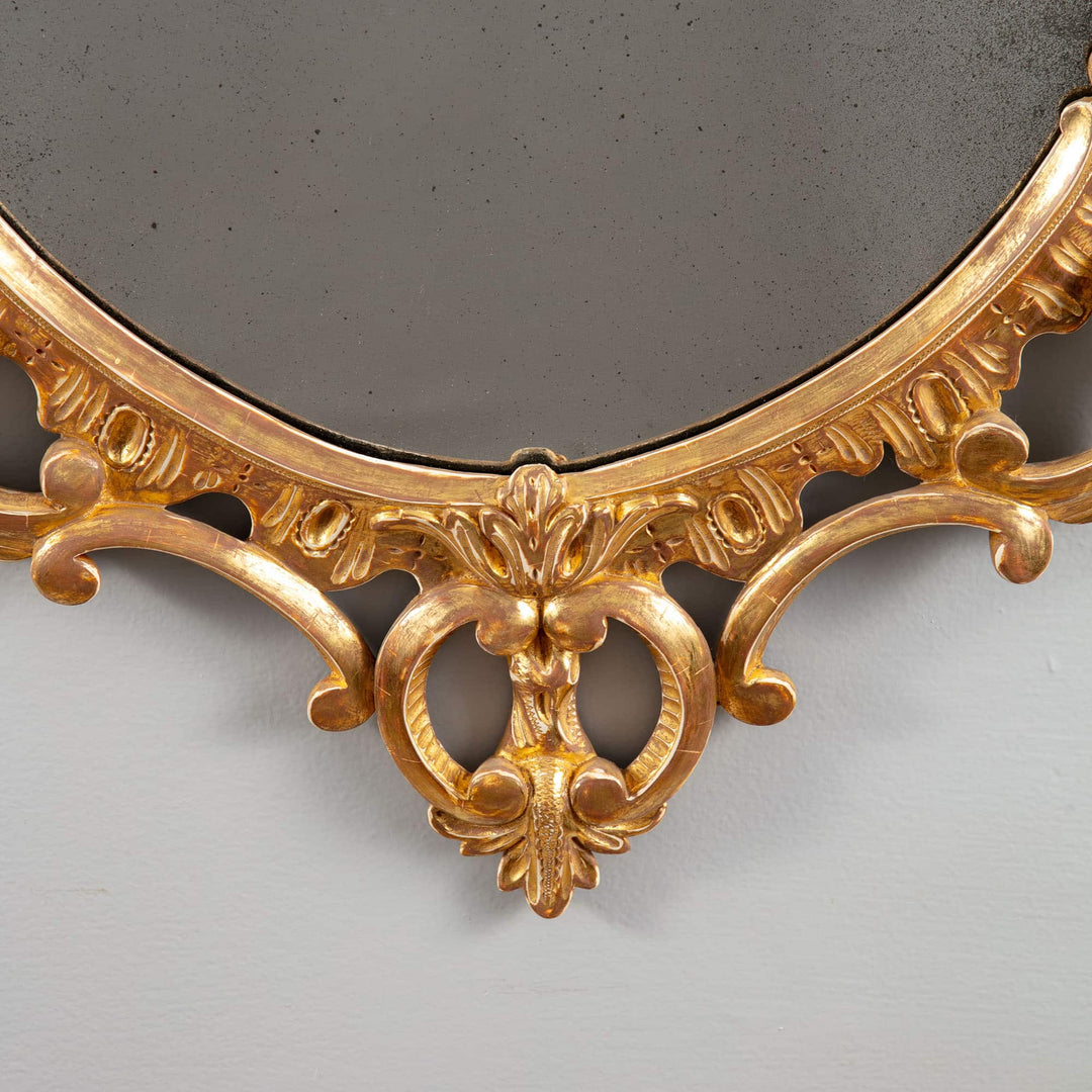 George III Rococo giltwood oval mirror with intricate C and S scrolls and floral swags, 18th century English design.