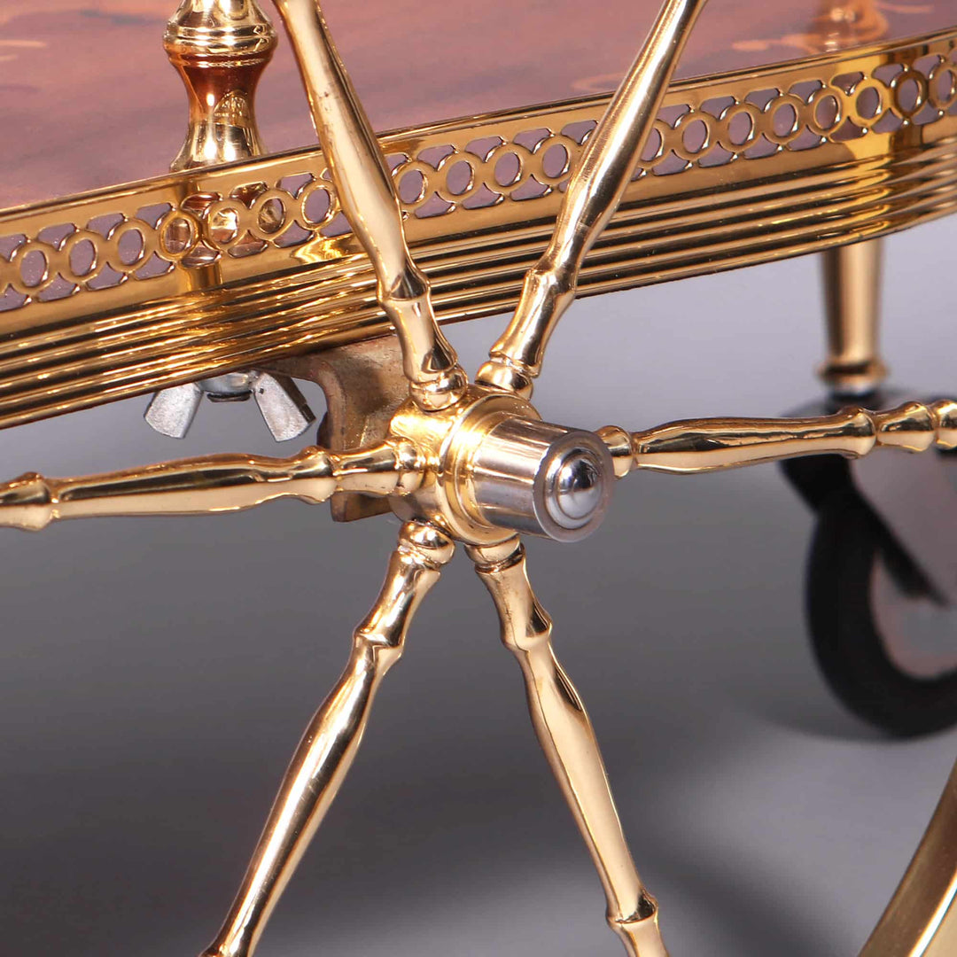 MID CENTURY ITALIAN MARQUETRY DRINKS TROLLEY detailed close-up of polished brass leg and wheel assembly.