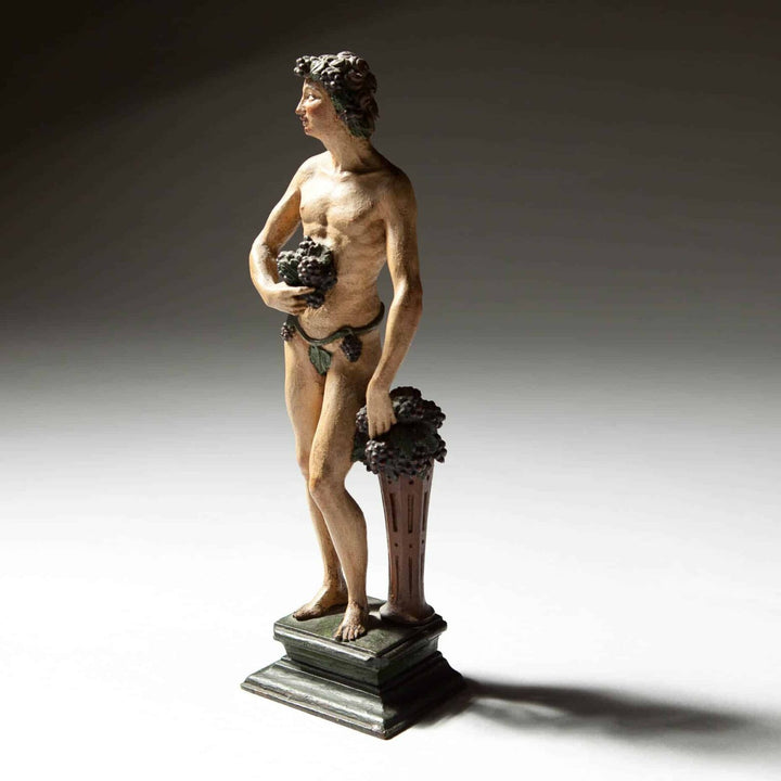 Flemish Carved Wooden Polychrome Figure Of Bacchus, 17th century sculpture of Bacchus with grapes on plinth.