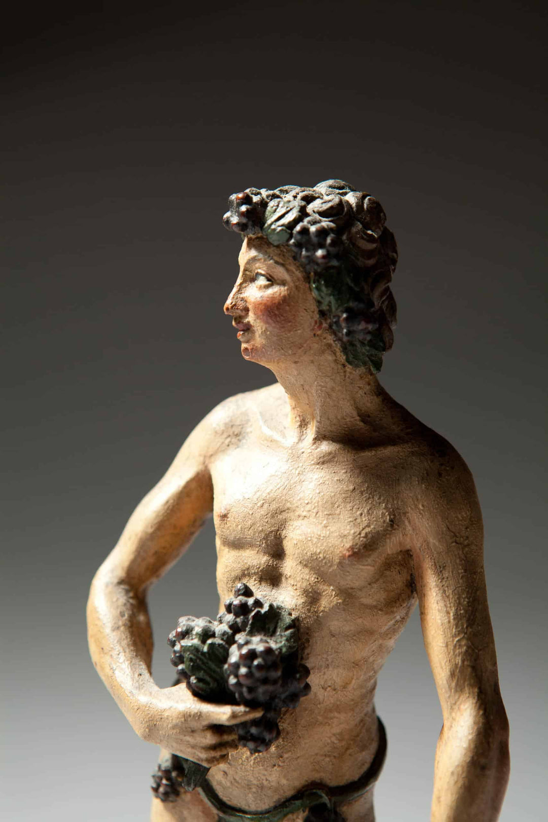 Flemish Carved Wooden Polychrome Figure Of Bacchus holding grapes with vine details, 17th century antique sculpture.
