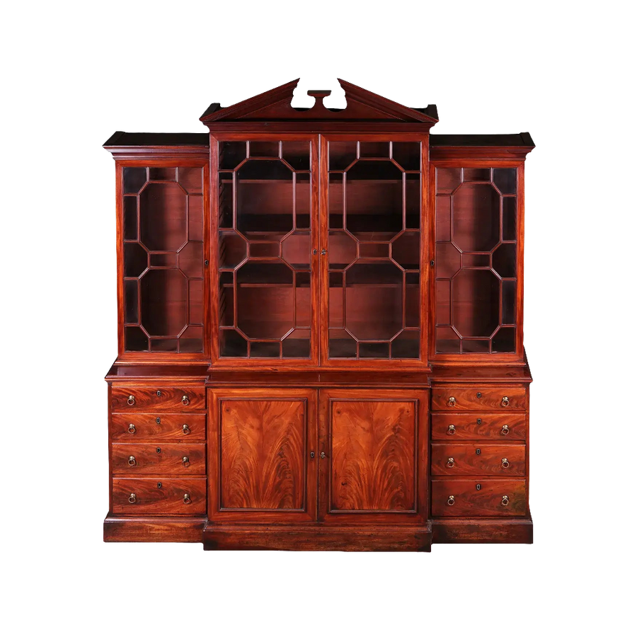 GEORGE III MAHOGANY BREAKFRONT BOOKCASE with glazed doors, drawers, and carved broken pediment circa 1770 England.