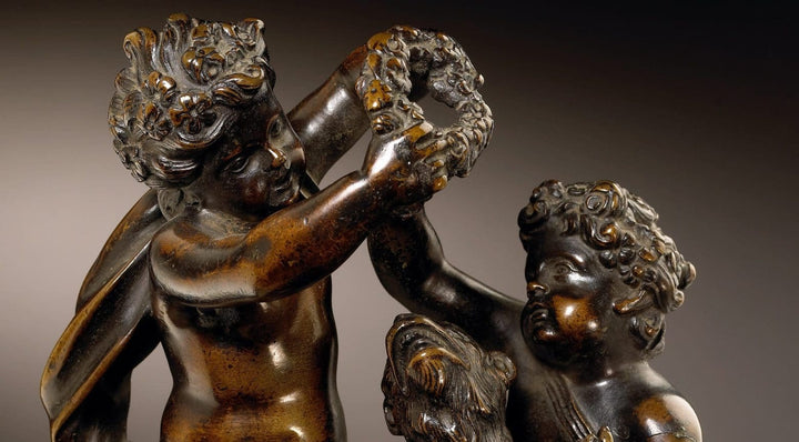 Pair of bronze cherub groups featuring playful cherubs with a monkey holding a garland, circa 1700.