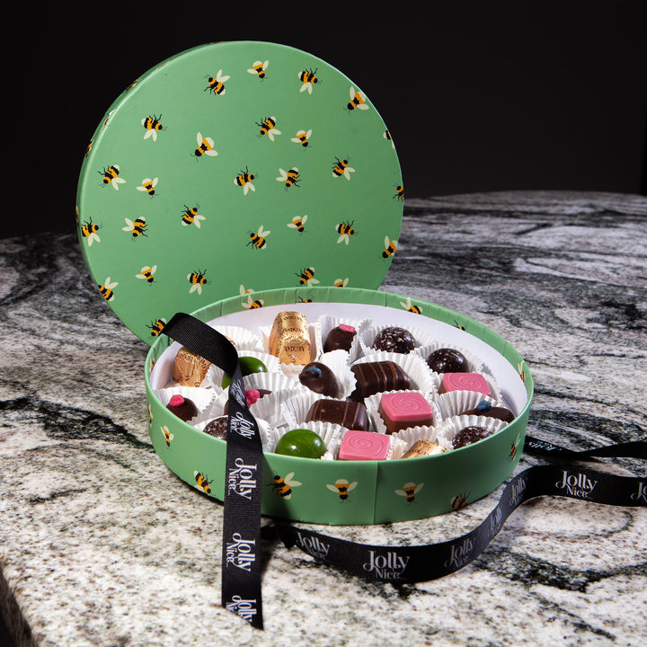 Green round box with bee pattern containing assorted chocolates and black ribbon from Nicholas Wells Antiques Christmas Hamper 2025