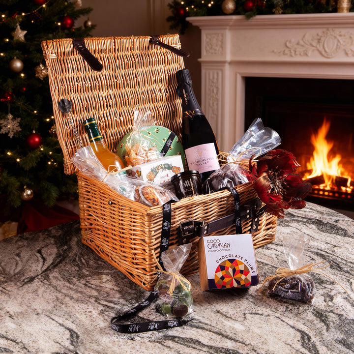 Christmas hamper by Nicholas Wells Antiques with regional treats and drinks in a wicker basket by a cozy fireplace