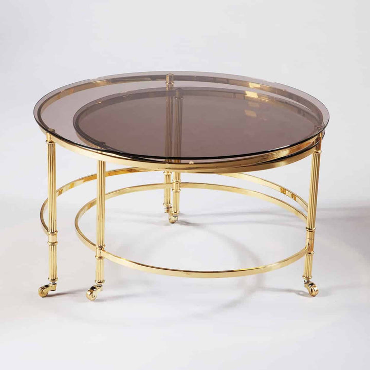 Mid Century Metamorphic Brass Coffee Table with circular smoked glass top and burnished brass frame on casters.