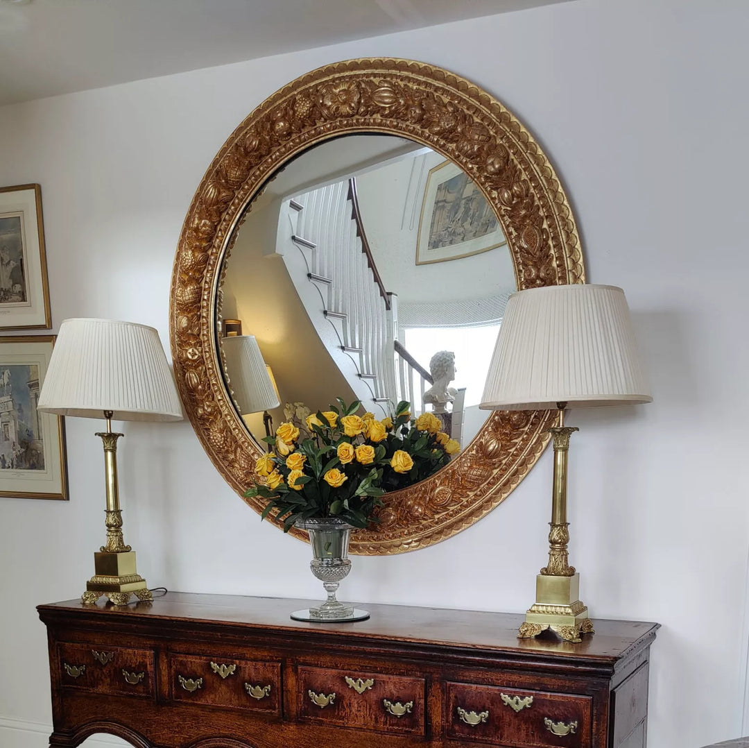 Monumental 5ft Round Italian Mirror with carved giltwood frame featuring fruits and foliage, 19th century Italy.
