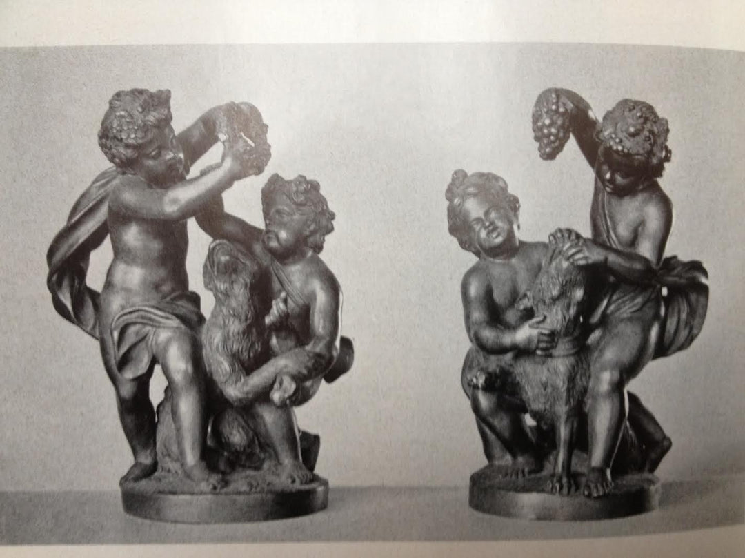 Pair of bronze cherub groups with one playing with a monkey and the other feeding grapes to a dog.