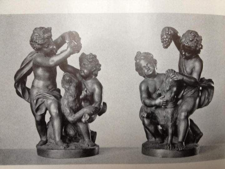 Pair of bronze cherub groups with one playing with a monkey and the other feeding grapes to a dog.