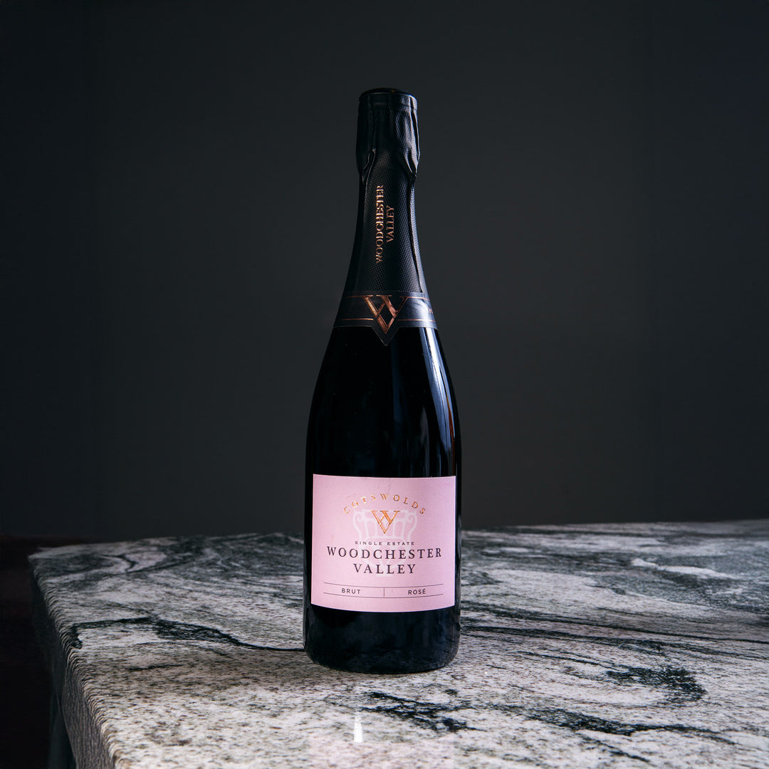 Bottle of Woodchester Valley sparkling wine on marble surface, part of Nicholas Wells Antiques Christmas Hamper 2025