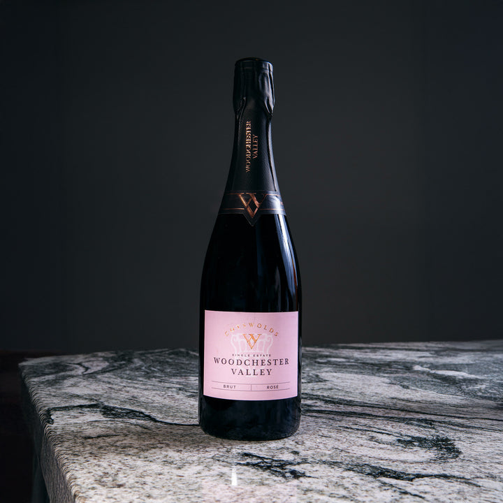 Bottle of Woodchester Valley sparkling wine on marble surface, part of Nicholas Wells Antiques Christmas Hamper 2025